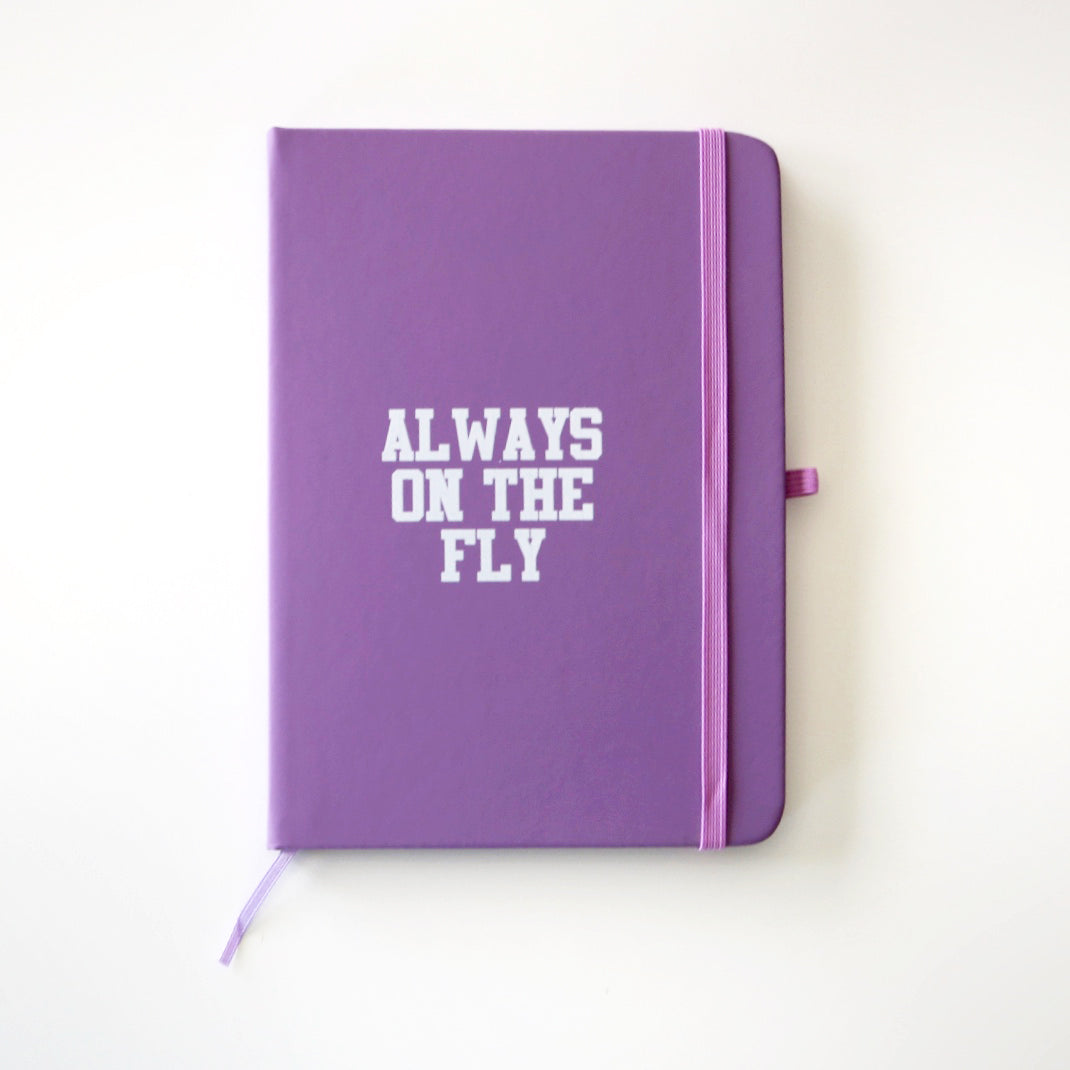 purple hardcover journal reading "Always on the fly" in a white font