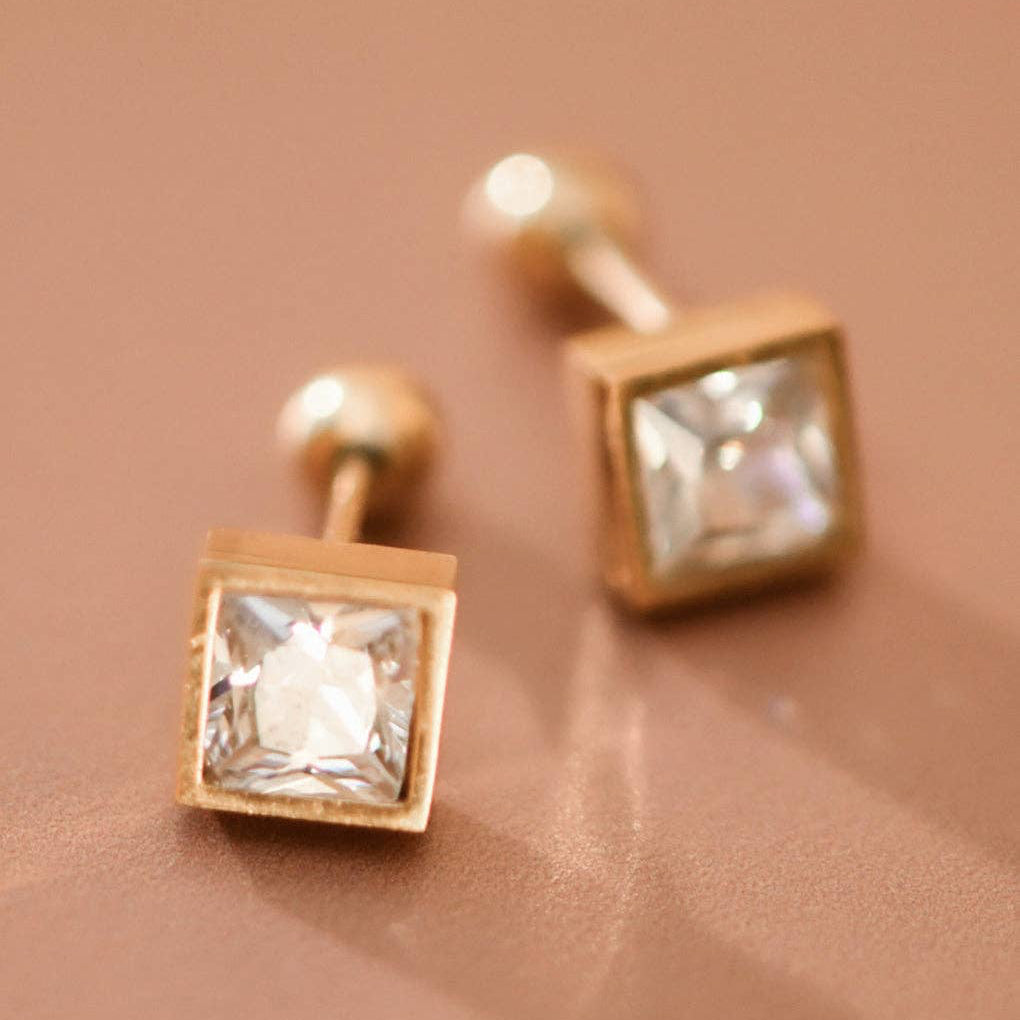 Elevate your everyday look with these delicate 18K gold plated stainless steel stud earrings, featuring sparkling clear crystals in a timeless square design. Measuring just 0.25" x 0.25", these petite studs offer understated elegance for any occasion. Crafted with hypoallergenic stainless steel, they're perfect for sensitive skin. The waterproof and tarnish-resistant finish ensures lasting brilliance—simply avoid prolonged contact with lotions, perfumes, and cleaning products to maintain their radiant shine