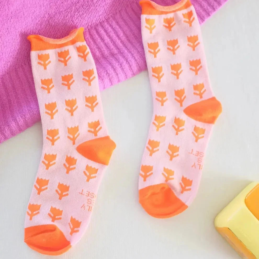 Step into spring with these vibrant Funky Tulip Socks, featuring bold orange and hot pink hues that instantly elevate any outfit. Crafted from a comfortable cotton-polyester blend, these playful socks deliver both style and wearability. Perfect for adding a pop of personality to your everyday look, whether paired with sneakers or sandals. Fits women's sizes 8-11. Make a colorful statement with every step.