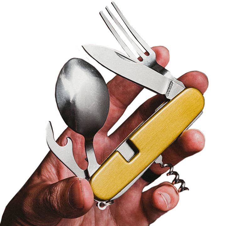 Multitool with knife, fork, and spoon held in a hand on a white background