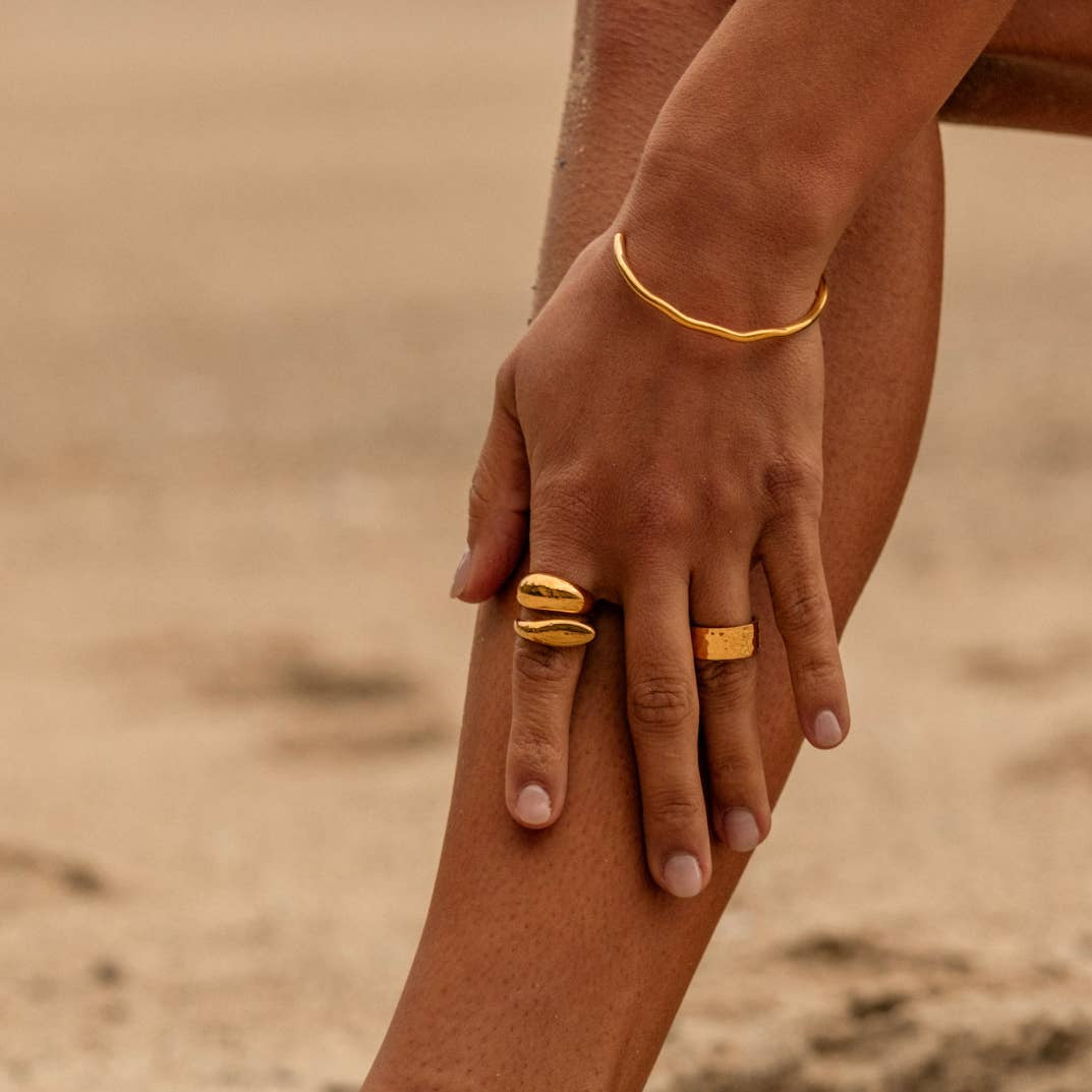Close-up of a hand with gold rings on a sandy background