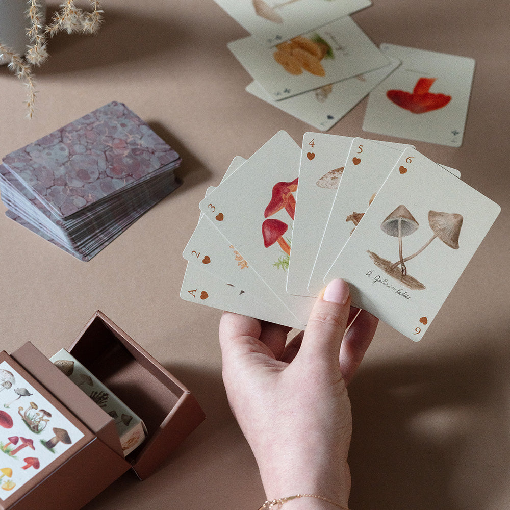 This Set of Two 52-Deck Playing Cards features incredible vintage drawings of fungi species from England and Wales dating back to 1860. Roomytown's design team in Bath, UK, have carefully adapted and enhanced the original artwork and applied it to each of the playing cards in this Set of Two 52-Deck Playing Cards that come stored in a premium quality flip-top card hinged box.