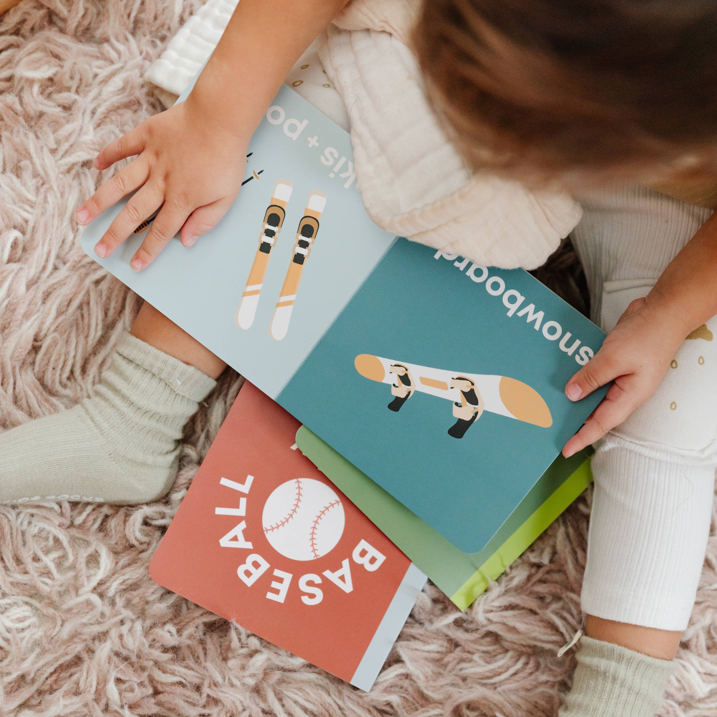 Child holding books with illustrations on a fluffy carpet