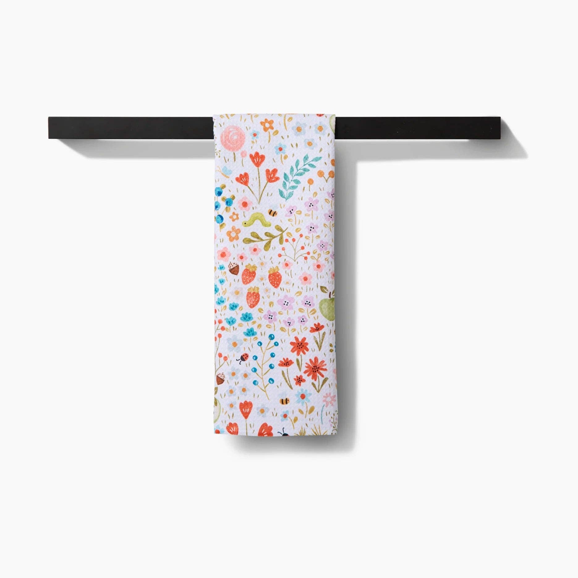 Floral-patterned towel hanging on a black metal rack against a white background