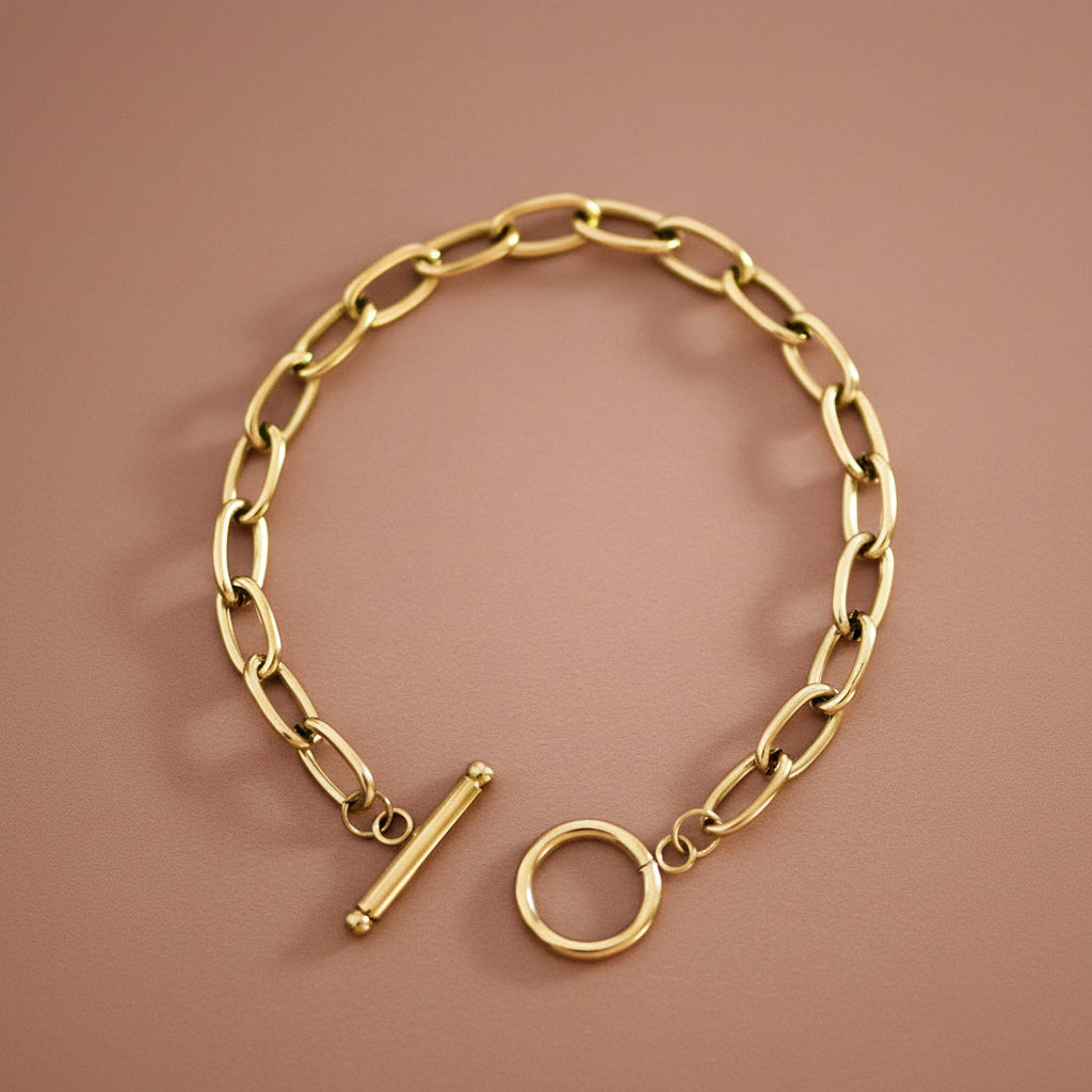 18K Gold Plated Stainless Steel Paperclip Chain Bracelet with Toggle Clasp. This bracelet features elongated paperclip-style links with a clean, modern silhouette and a classic toggle closure. This item is hypoallergenic, waterproof and tarnish-resistant. To prolong the shine and finish of the gold plating, contact with chemicals such as lotions, perfumes, and cleaning products should be avoided.
