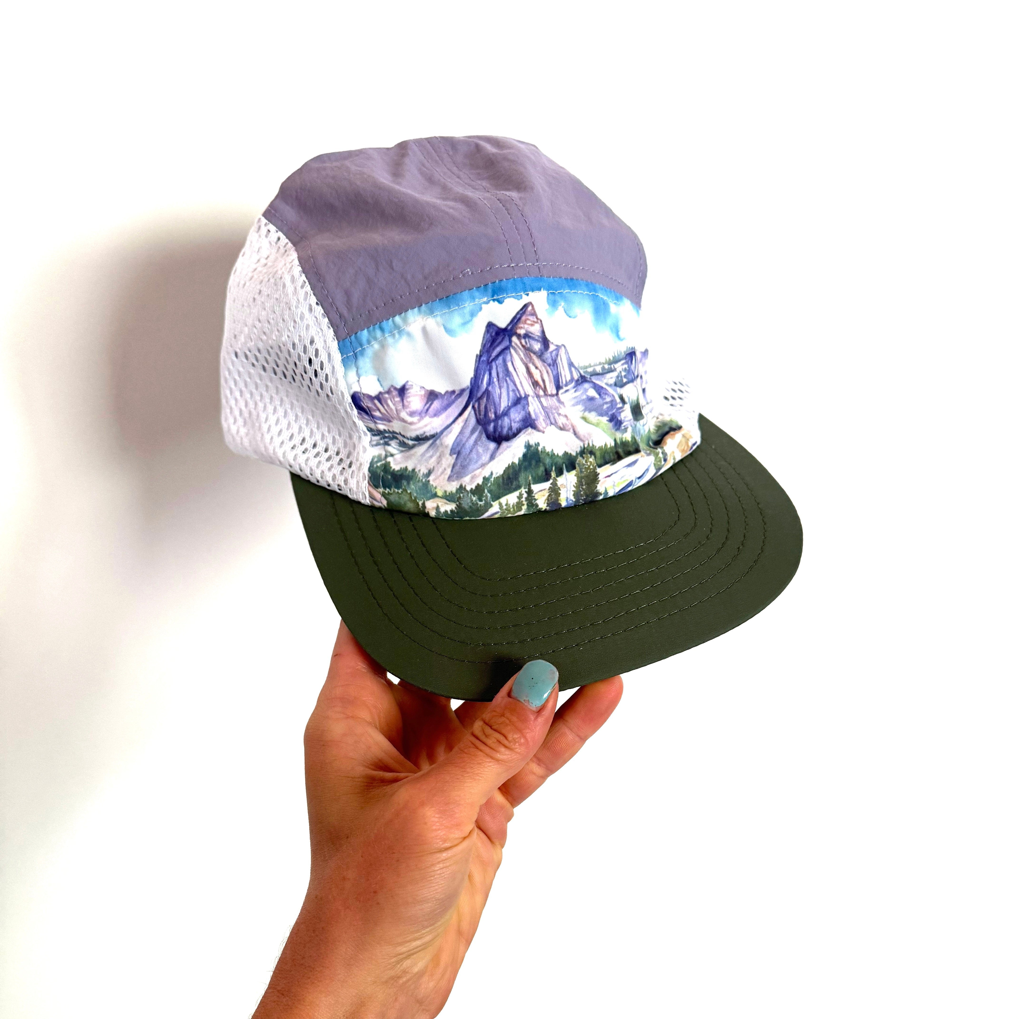 purple and dark green snap back hat featuring a painting of lake blanche