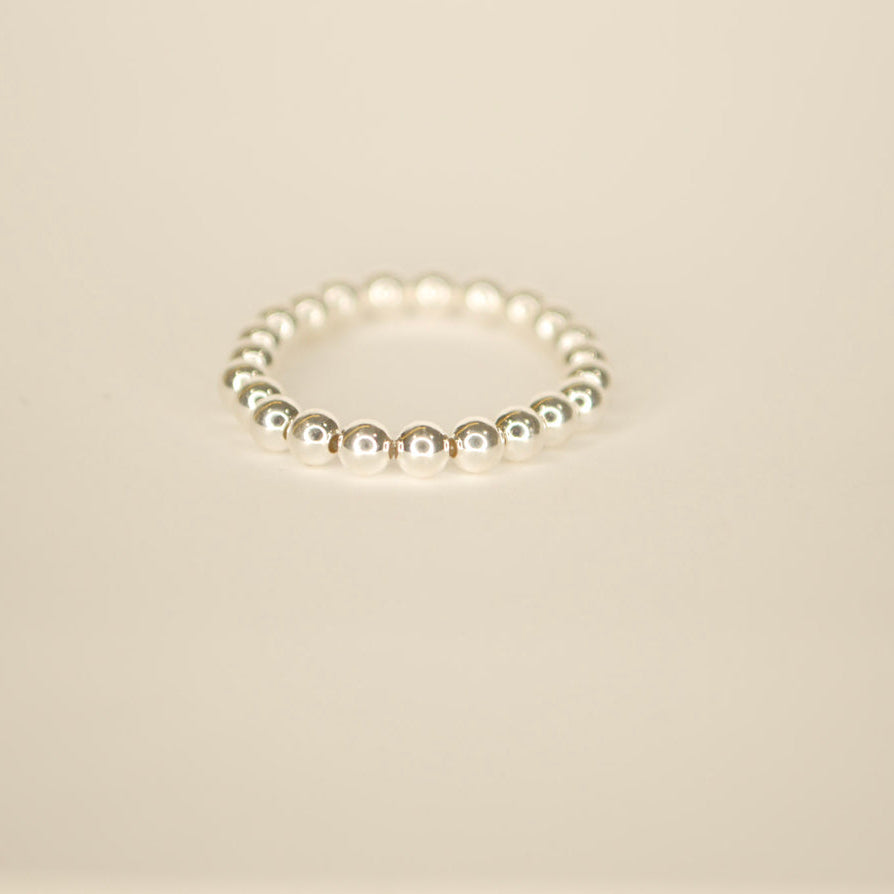 Silver beaded ring on an off white back ground.