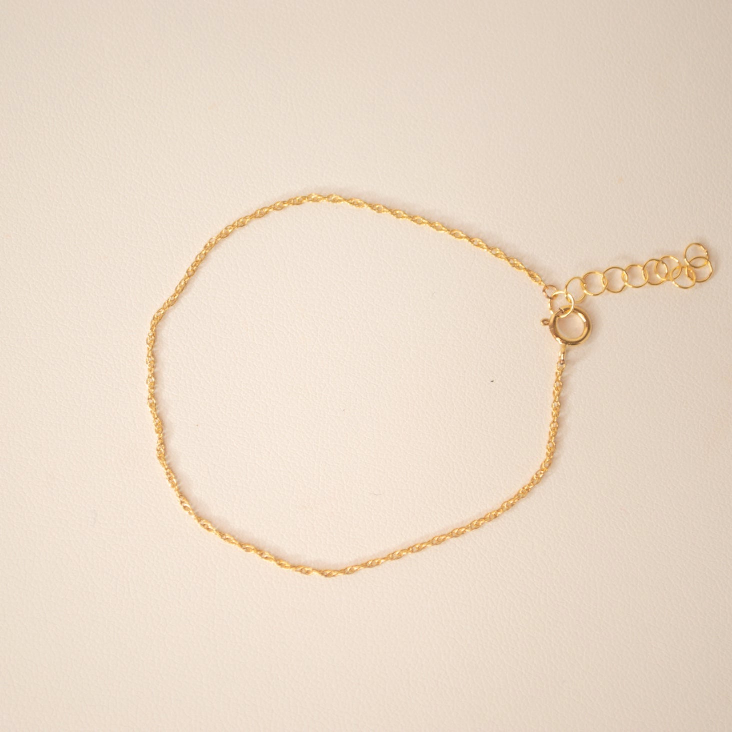 Gold bracelet against an off white back ground.