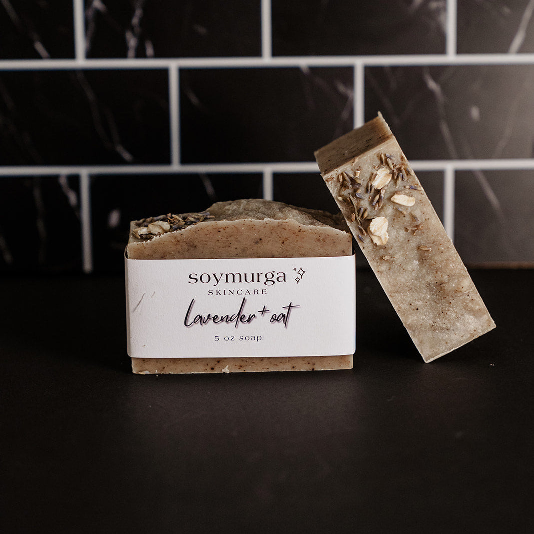 Lavender + Oat soap bar on a black countertop with black marble subway tile in the background.