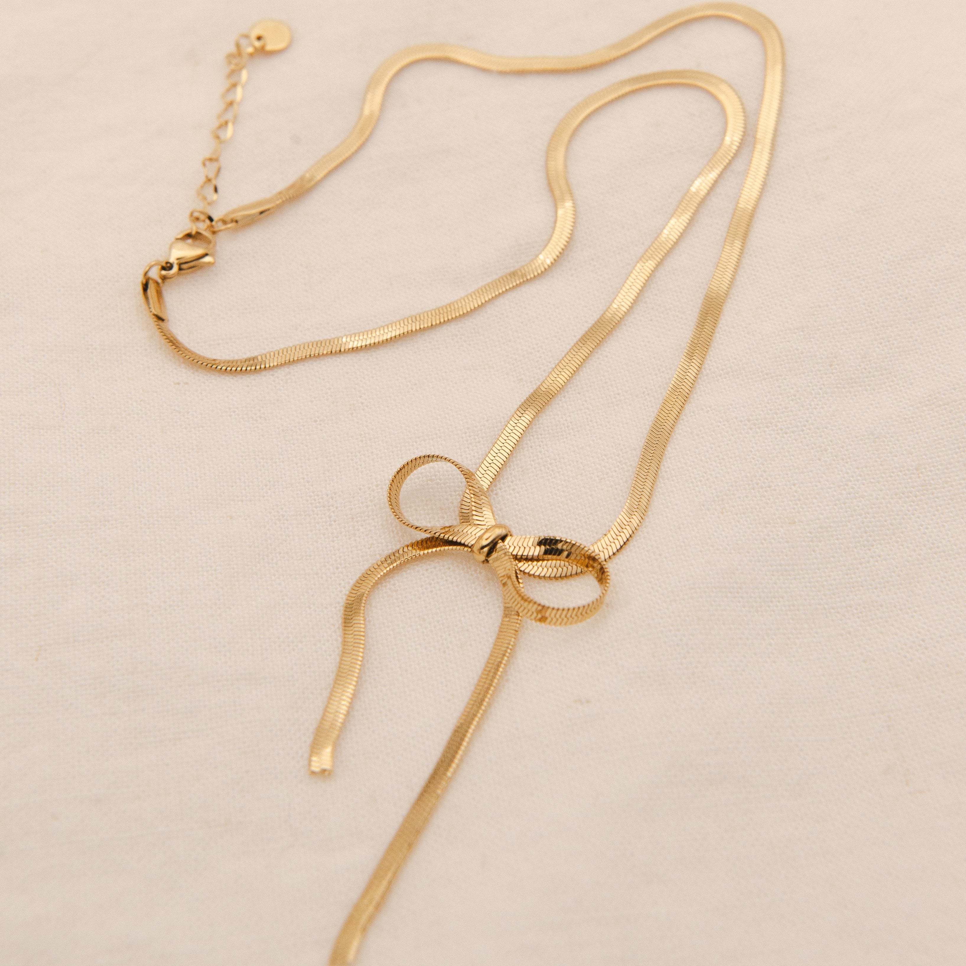 Gold ribbon-shaped chain tied into a bow at the center