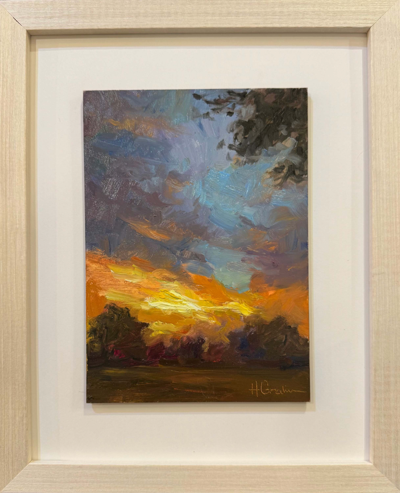 A landscape scene of dusk. The sky is blue and purple in the foreground and in the farther point of view it is golden with bright orange and yellow hues.