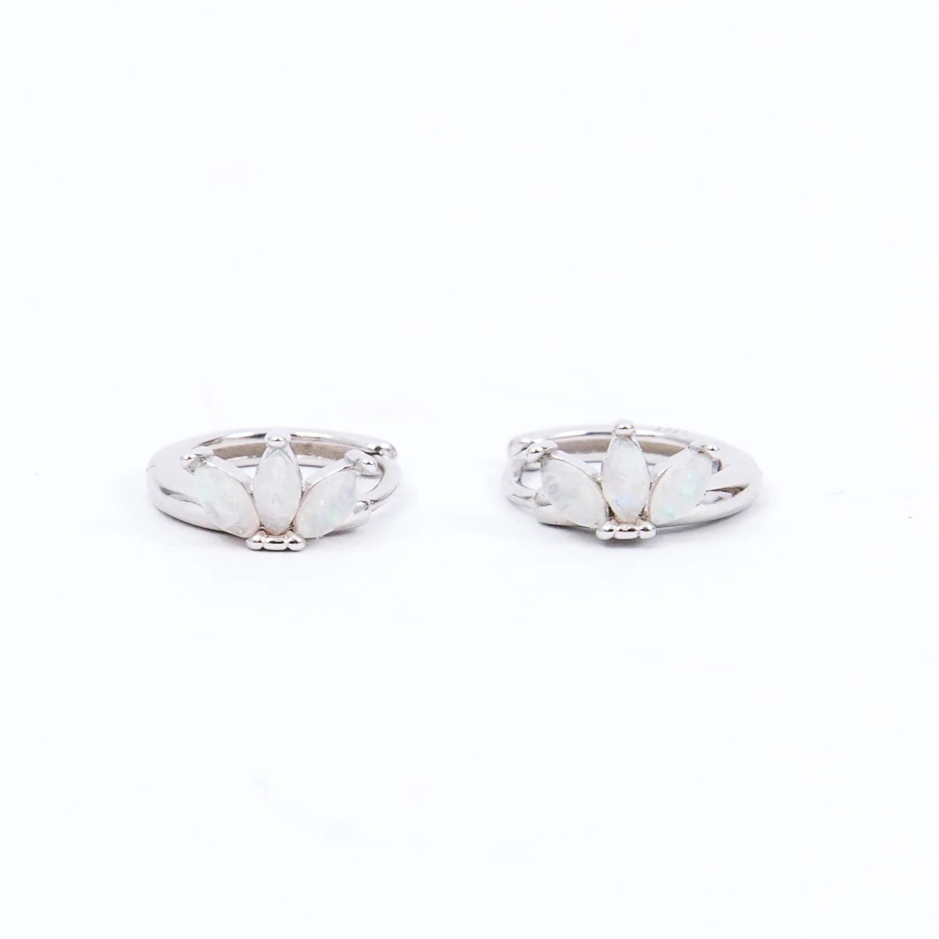 delicate opal and silver huggie earrings in front of white background The earring features a trio of marquise-shaped opals arranged in a fan or floral design, giving it a soft, feminine aesthetic with a subtle shimmer.