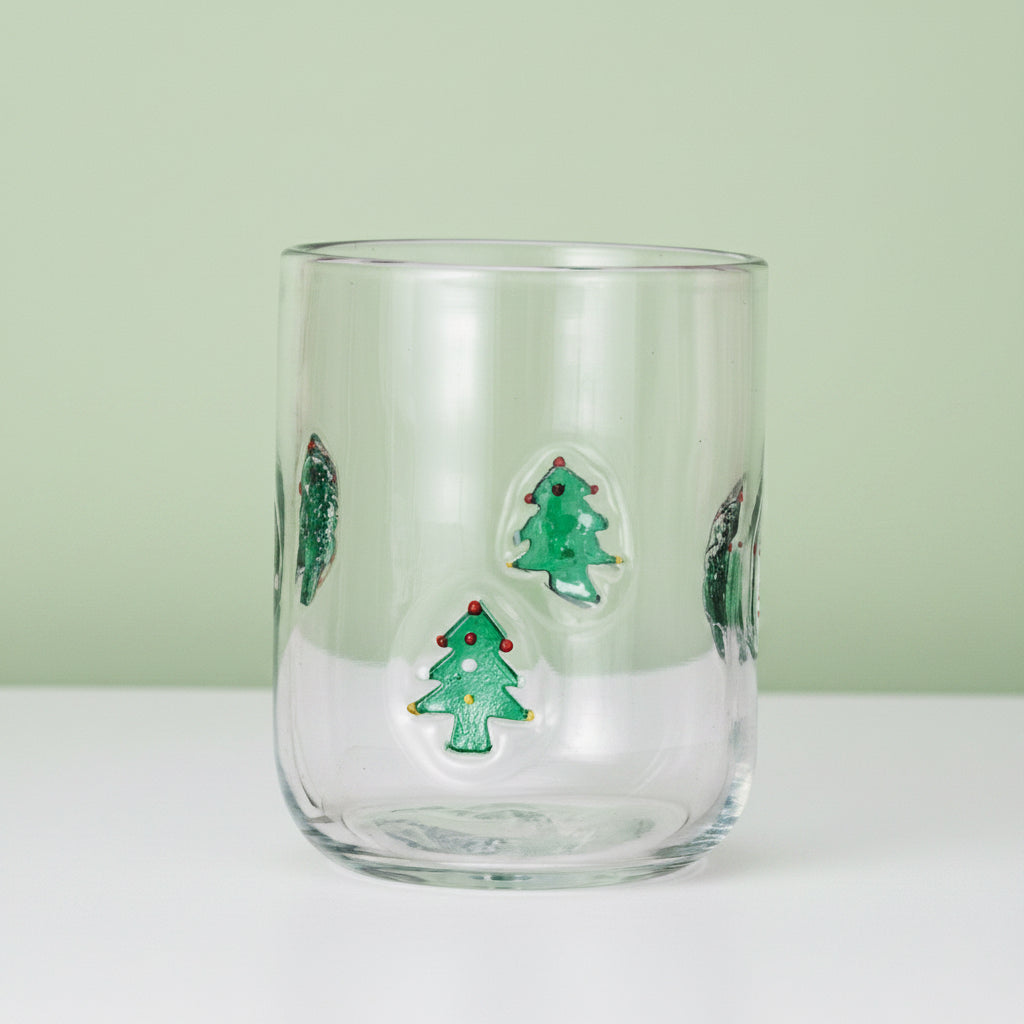 Clear glass tumbler with Christmas tree designs on a white background