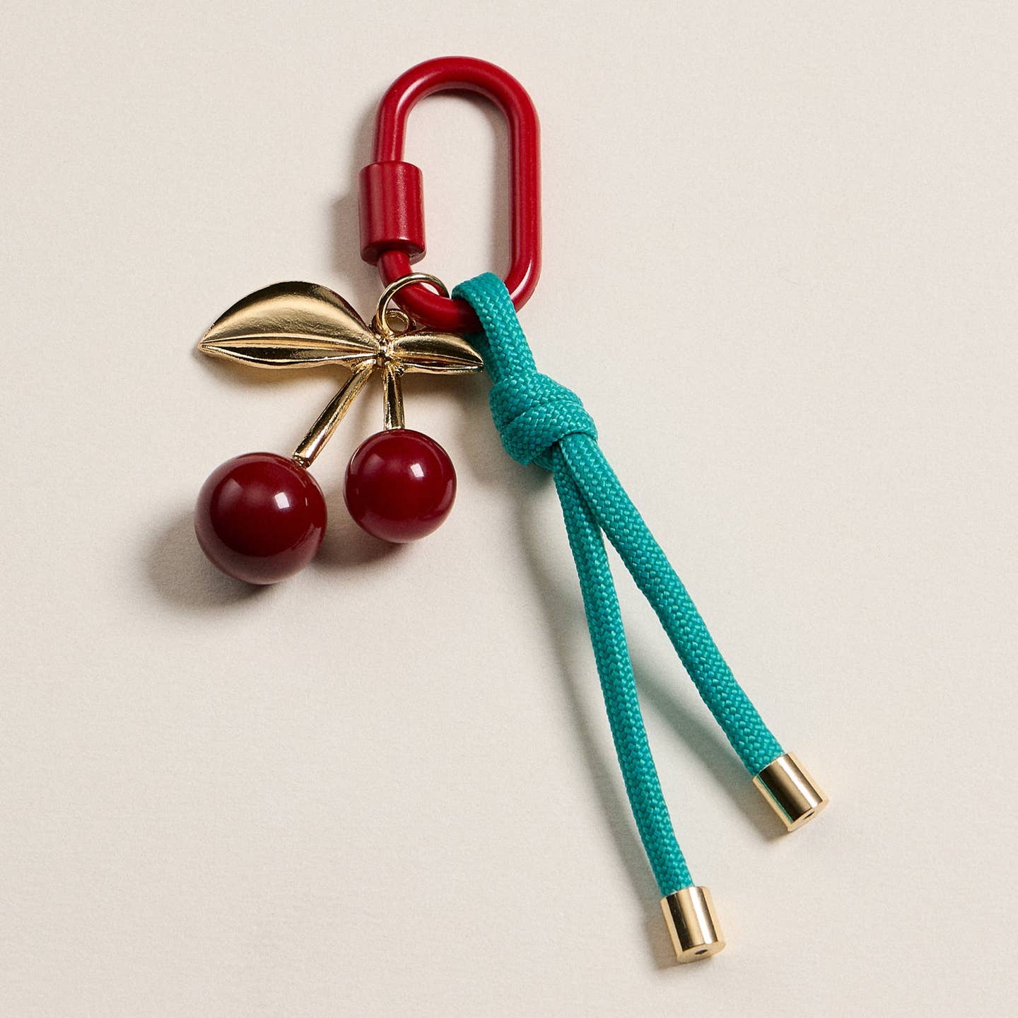 Add a pop of fun to your accessories with this enamel cherry charm keychain. Featuring a glossy red cherry with gold-tone leaves, paired with a vibrant teal rope and red clasp, this keychain brings playful charm to your keys, bags, or purses. Lightweight and colorful, it’s the perfect everyday accessory.