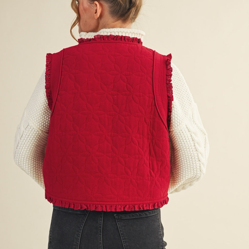 Elevate your layering game with this charming red floral quilted vest. Crafted from soft quilted fabric adorned with delicate floral patterns, it features a front-tie closure that lets you customize the fit to your comfort. The pretty lace trim adds a touch of feminine elegance to any outfit. Perfect for layering over your favorite tees or dresses, this versatile piece brings warmth and style to your everyday wardrobe.