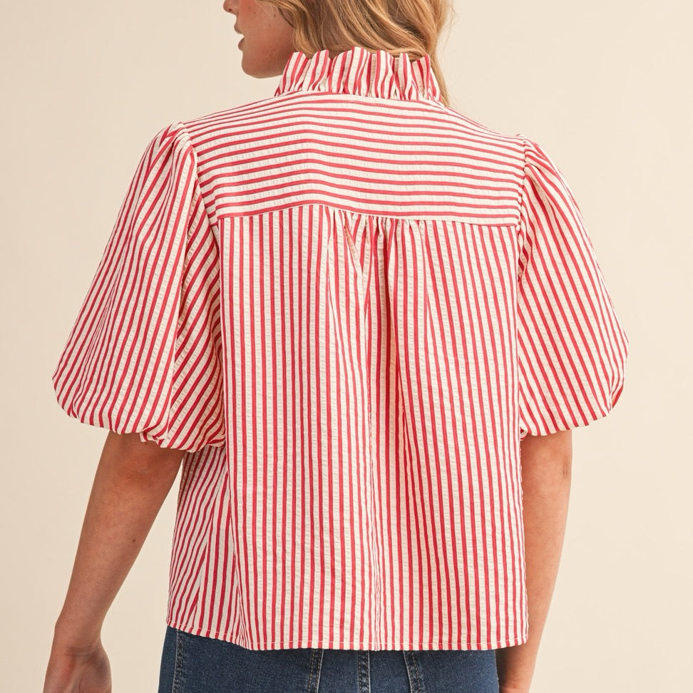Elevate your everyday wardrobe with this charming berry red striped button-down blouse. The delicate ruffled detailing adds a touch of feminine flair, while the classic pin stripe pattern keeps things polished and versatile. Short sleeves make it perfect for layering or wearing solo during warmer months. The functional button-down front allows for easy styling—wear it buttoned up for a put-together look or leave it partially open over a camisole for effortless sophistication. A wardrobe essential that works