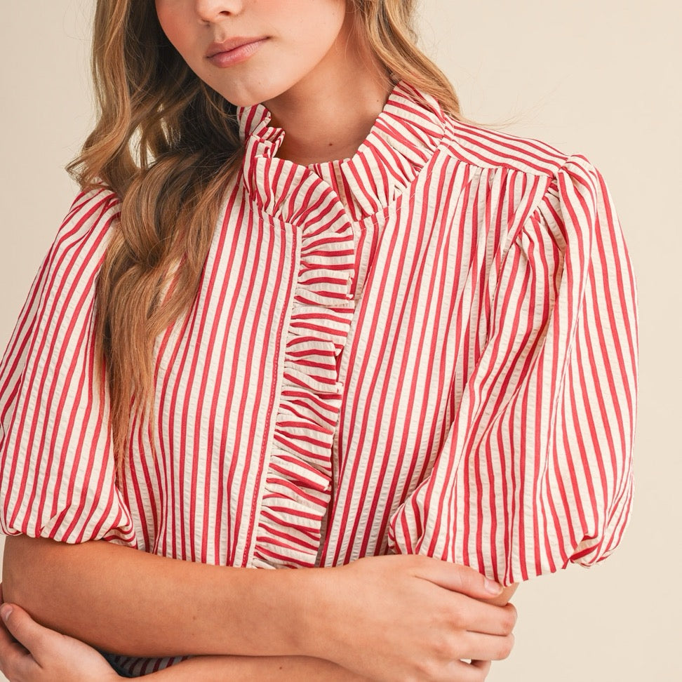 Elevate your everyday wardrobe with this charming berry red striped button-down blouse. The delicate ruffled detailing adds a touch of feminine flair, while the classic pin stripe pattern keeps things polished and versatile. Short sleeves make it perfect for layering or wearing solo during warmer months. The functional button-down front allows for easy styling—wear it buttoned up for a put-together look or leave it partially open over a camisole for effortless sophistication. A wardrobe essential that works