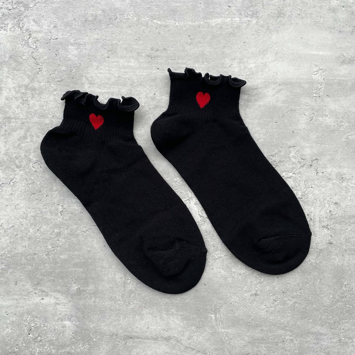 Cozy crew socks designed to brighten your everyday moments. These casual socks feature a charming single red heart detail near the top and delicate ruffled edges that add a playful touch. The soft, supportive construction keeps your feet comfortable all day long, whether you're relaxing at home or out and about. A sweet way to show yourself some love with every step.