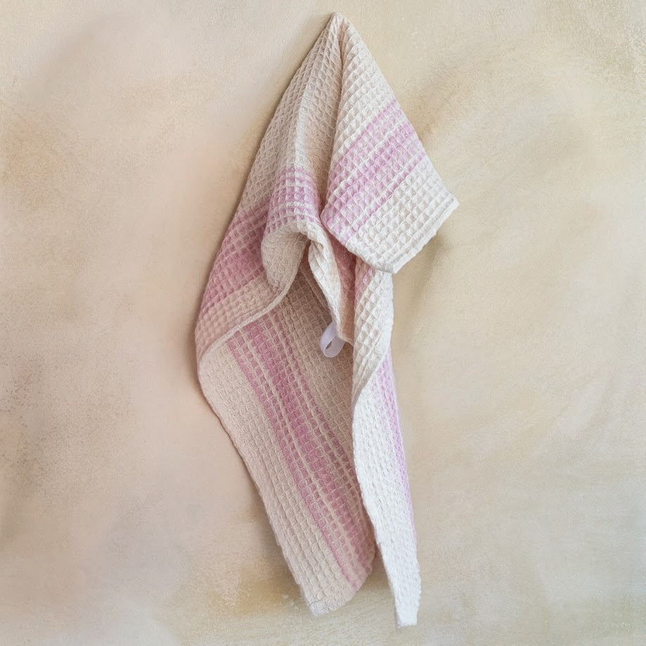 Woven pink and beige towel on a soft beige background