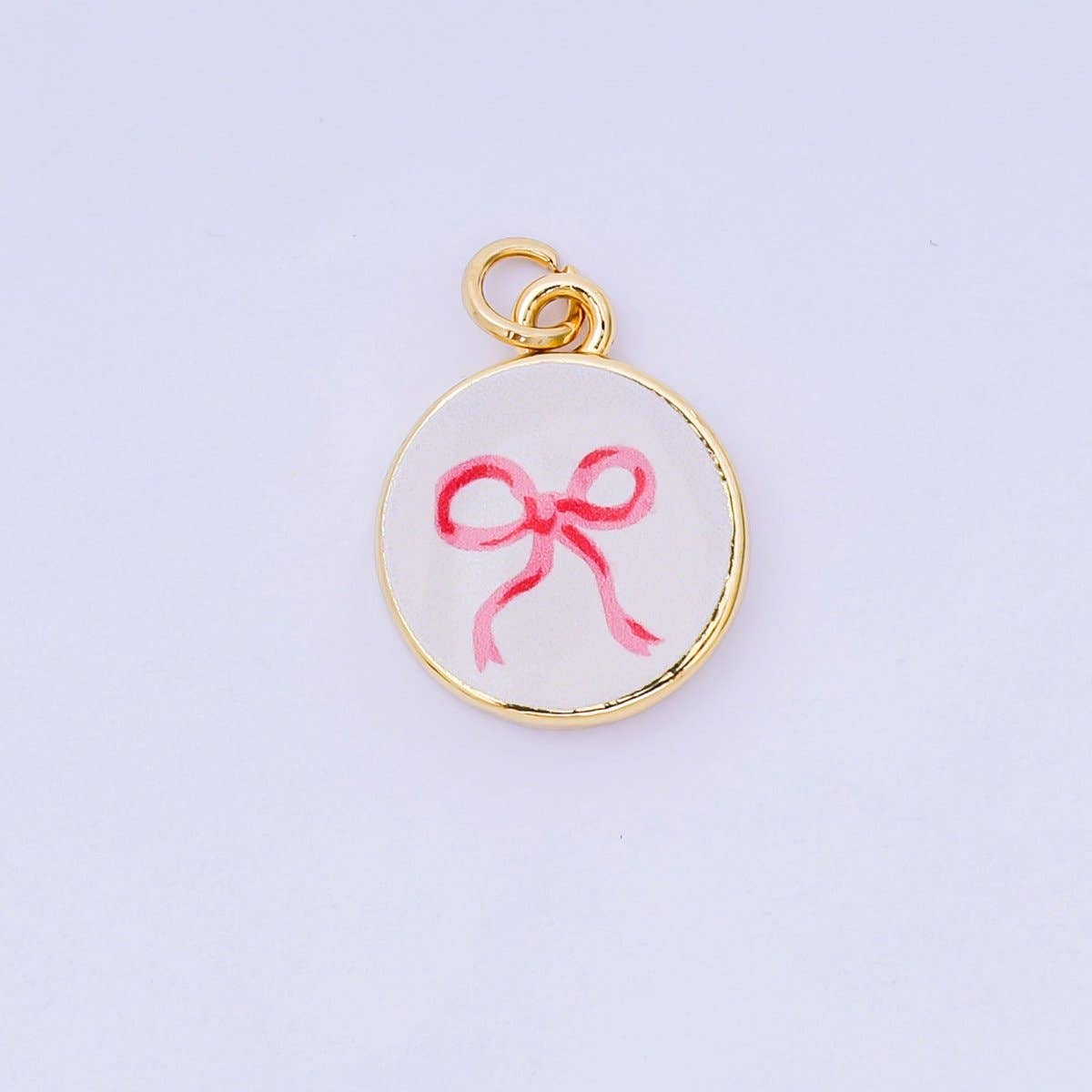 Delicate pink bow charm crafted in brass with 24K gold-filled details and vibrant enamel finish. Perfect for personalizing bracelets, necklaces, or charm collections. Measuring 17.9mm x 14.9mm, this petite pendant adds a touch of elegance to any piece. Lead-free and nickel-free for sensitive skin.