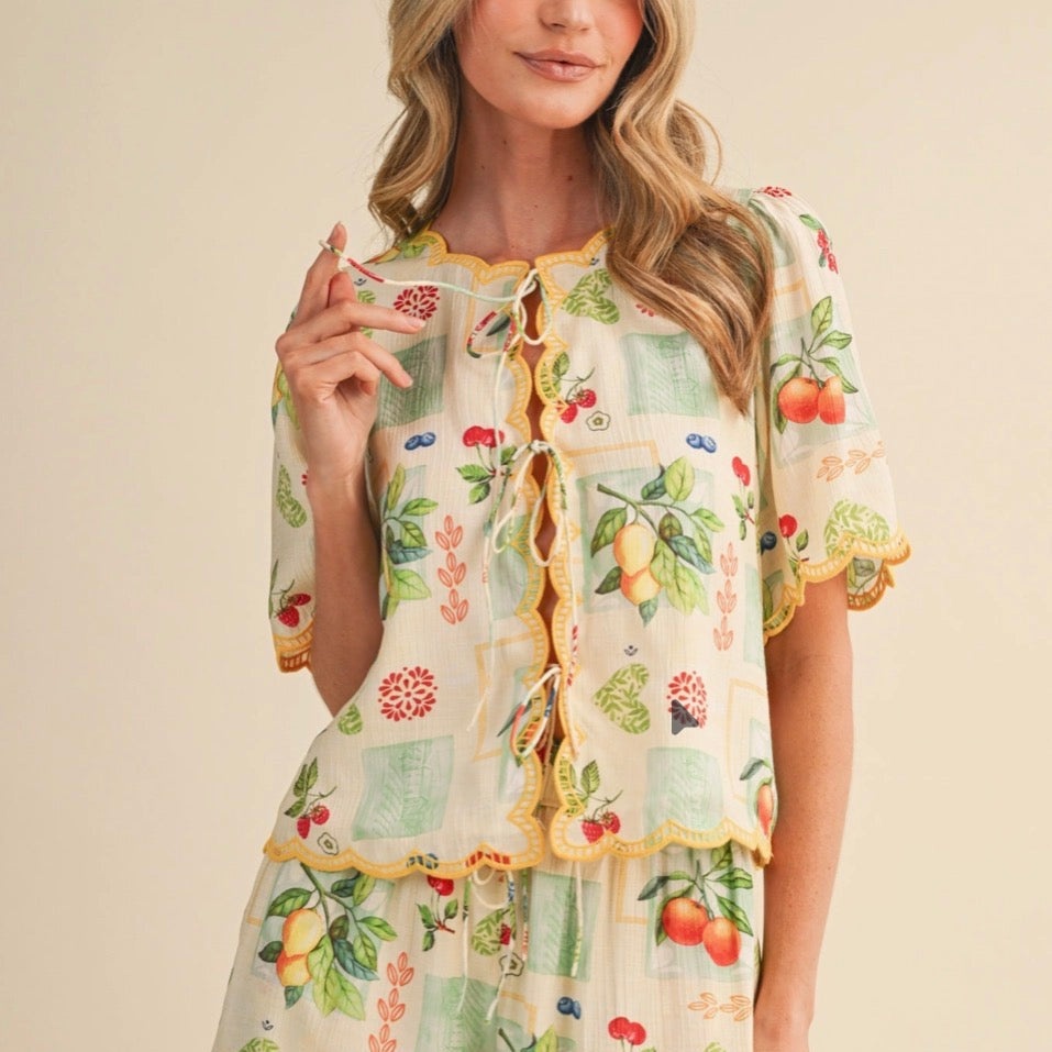 Celebrate your unique style with this charming Fruit Print Embroidered Scallop Top. Delicate embroidered details frame the neckline, cuffs, and hem, creating a playful, feminine silhouette that feels both timeless and fresh. The soft scalloped edges add a touch of vintage-inspired elegance, while the short sleeves keep you comfortable all season long. Perfect for layering or wearing solo, this top brings warmth and personality to any outfit. Designed by &MERCI with care.