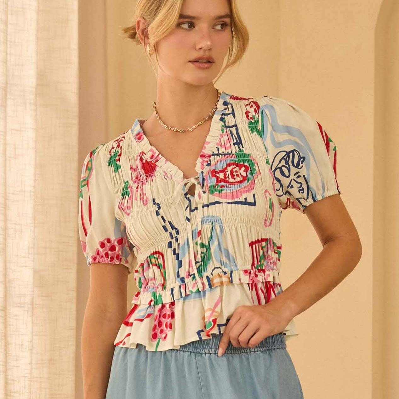 Feminine and flattering, this short sleeve top features a playful print and a peplum hem for a soft, waist-defining silhouette. Smocking detail adds texture and charm, making it perfect for pairing with tailored pants or denim for a chic, effortless look.