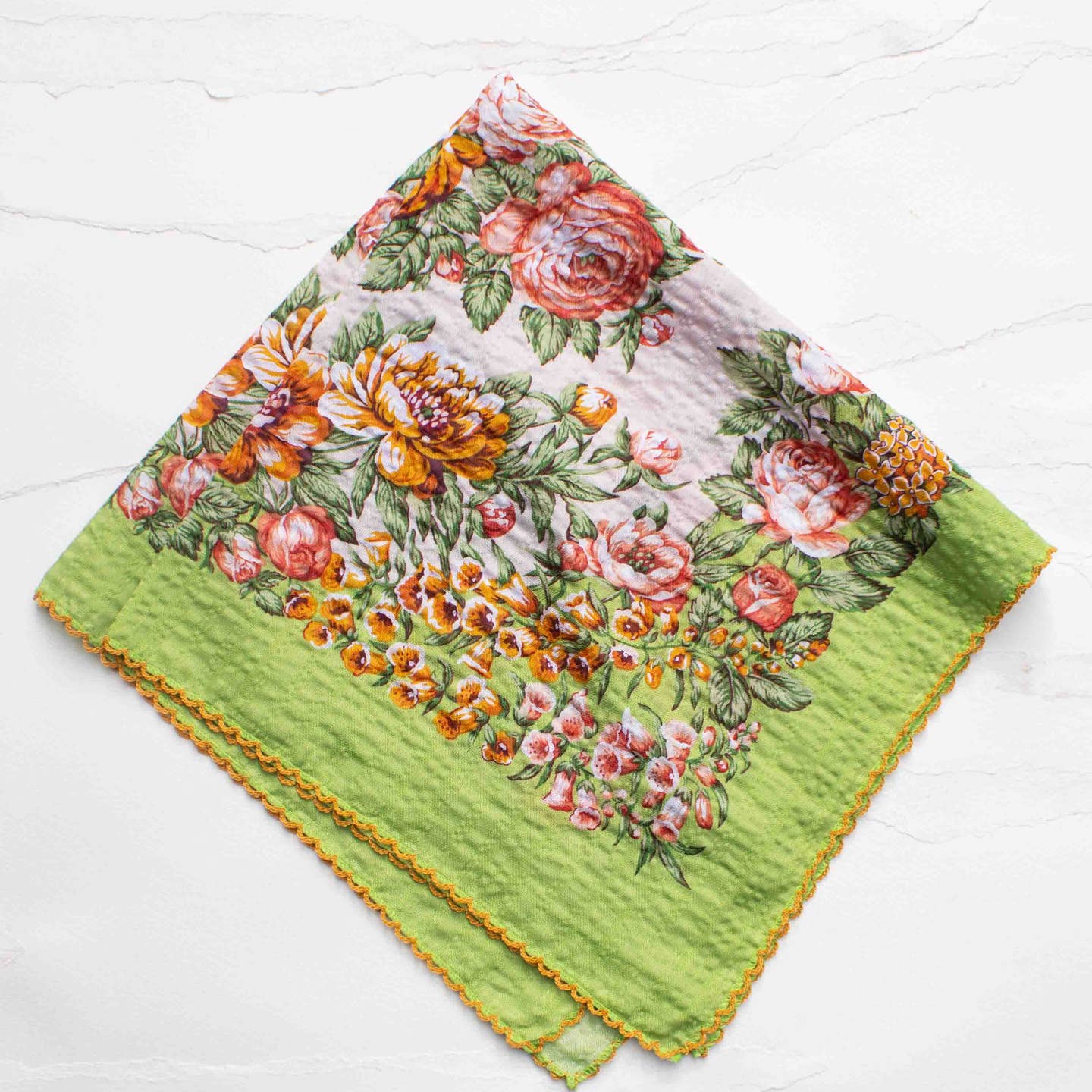 A romantic floral scarf inspired by vintage botanical prints. Featuring warm-toned blossoms on a soft green border, this piece adds a fresh yet nostalgic touch to any outfit. Lightweight and breathable, it can be styled as a neck scarf, hair accessory, bag accent, or even a pocket square. The delicate scalloped edge detail gives it a charming, feminine finish.