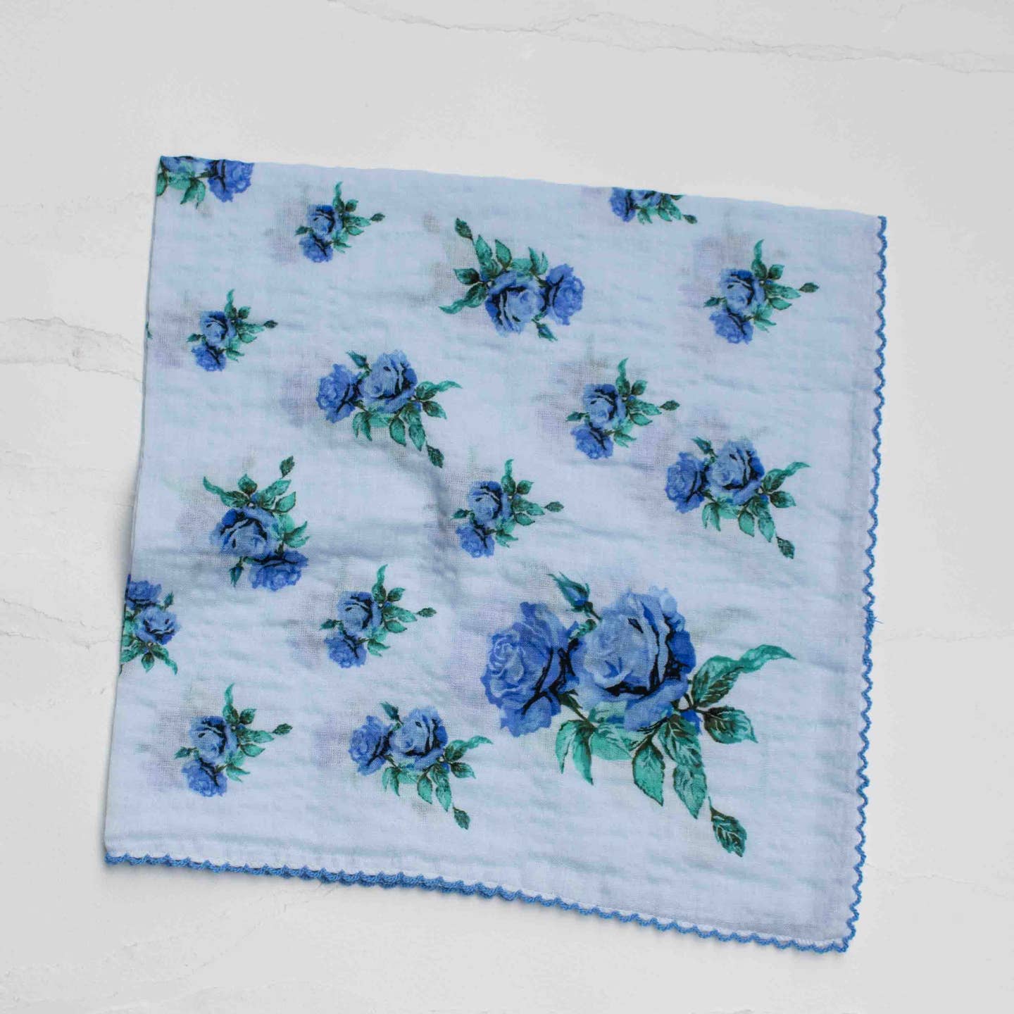 Add a soft, romantic touch to any look with this vintage-inspired floral scarf. Featuring delicate rose prints in a variety of colorways, this versatile piece is perfect for everyday styling. The lightweight cotton-rayon blend offers a breathable, silky-soft feel with a gentle drape, making it ideal for all seasons.
Designed in a classic square shape, it can be styled as a neck scarf, head wrap, hair accessory, or tied onto a bag for an effortless accent. Finished with a subtle scalloped edge.