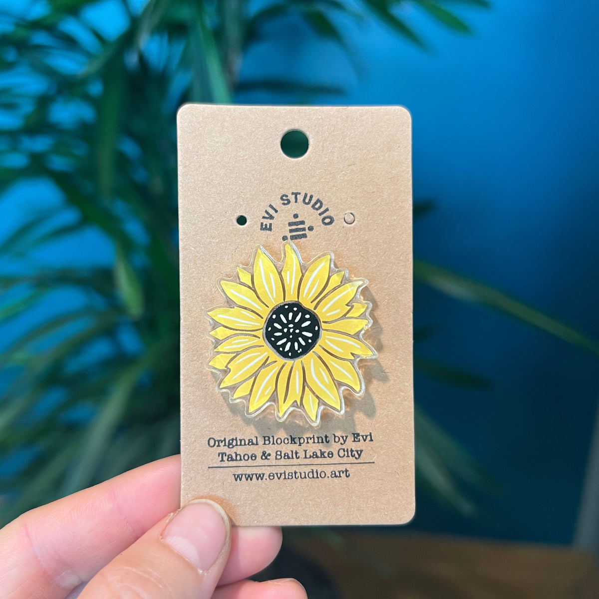 Yellow sunflower pin held in woman's hand.