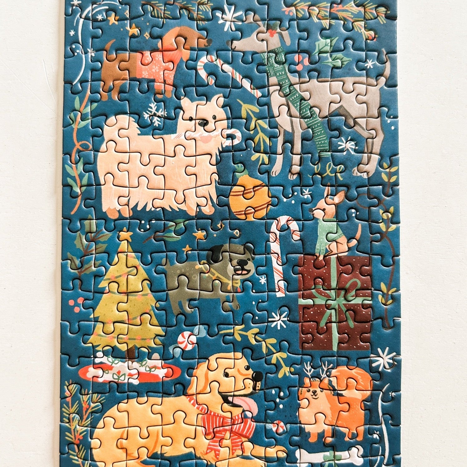 Completed puzzle depicting whimsical playing with Christmas decor and presents. Pictured against a white back ground.