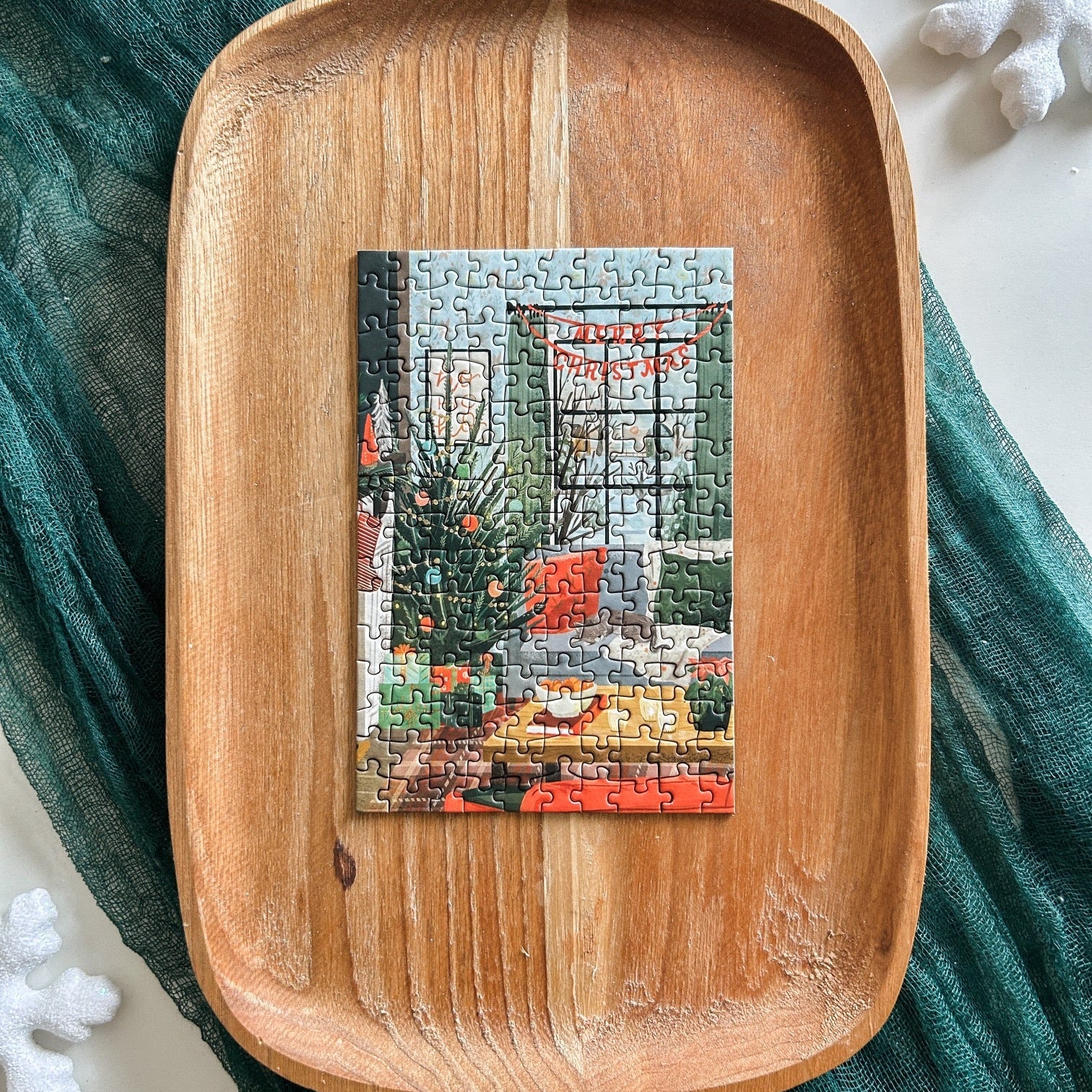 Finished puzzle against a wooden tray with a dark green table runner and frosty snowflake decorations.