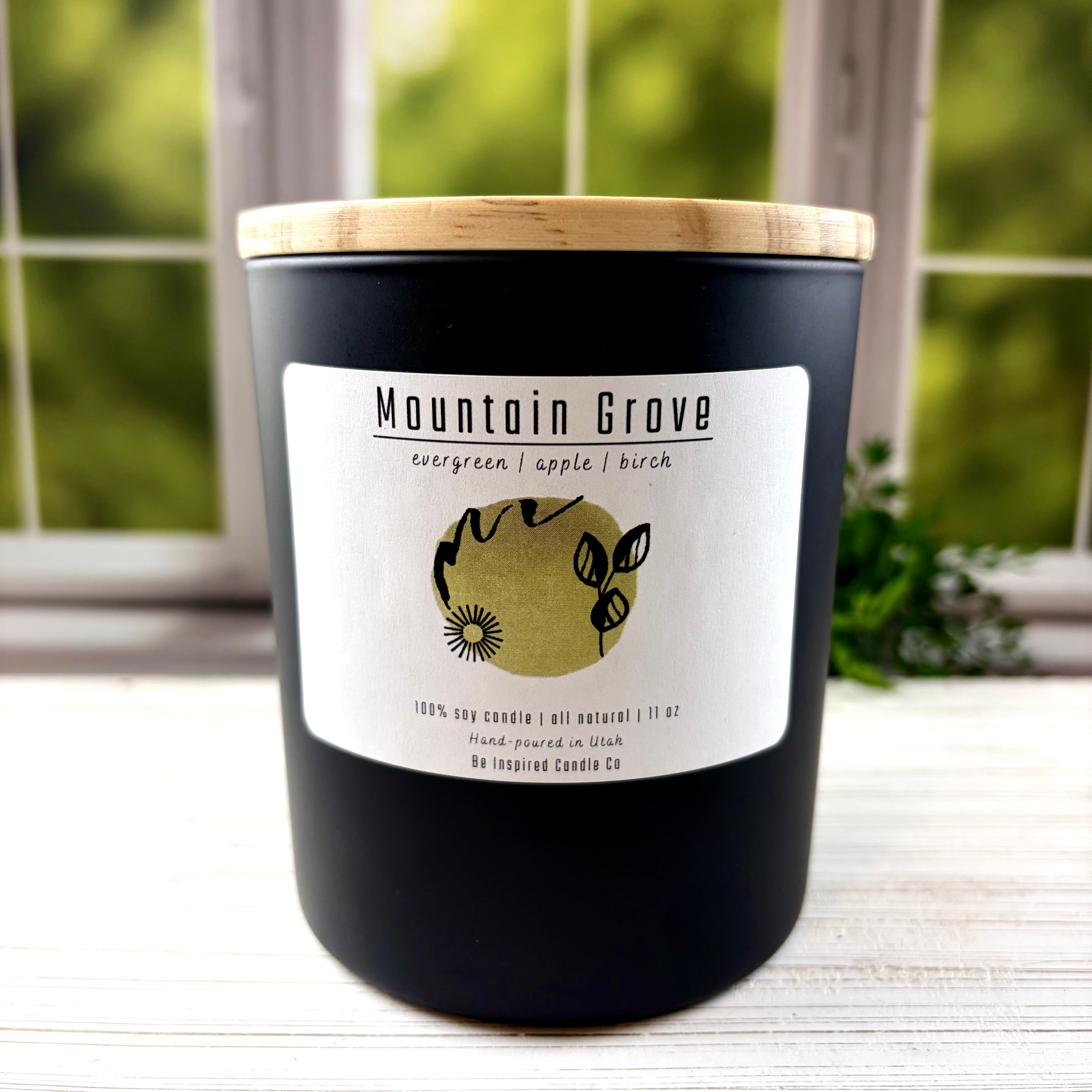 Large black candle with wooden lid and white label.