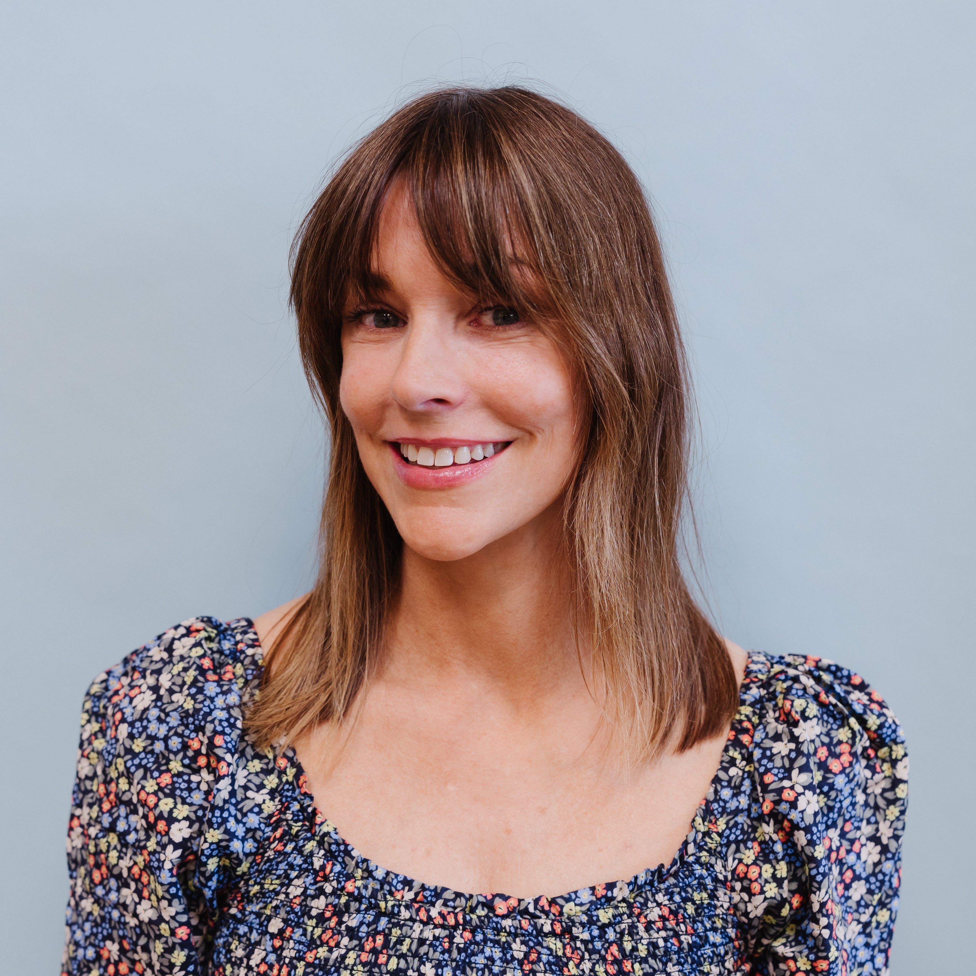 Woman wearing a floral blouse against a plain background