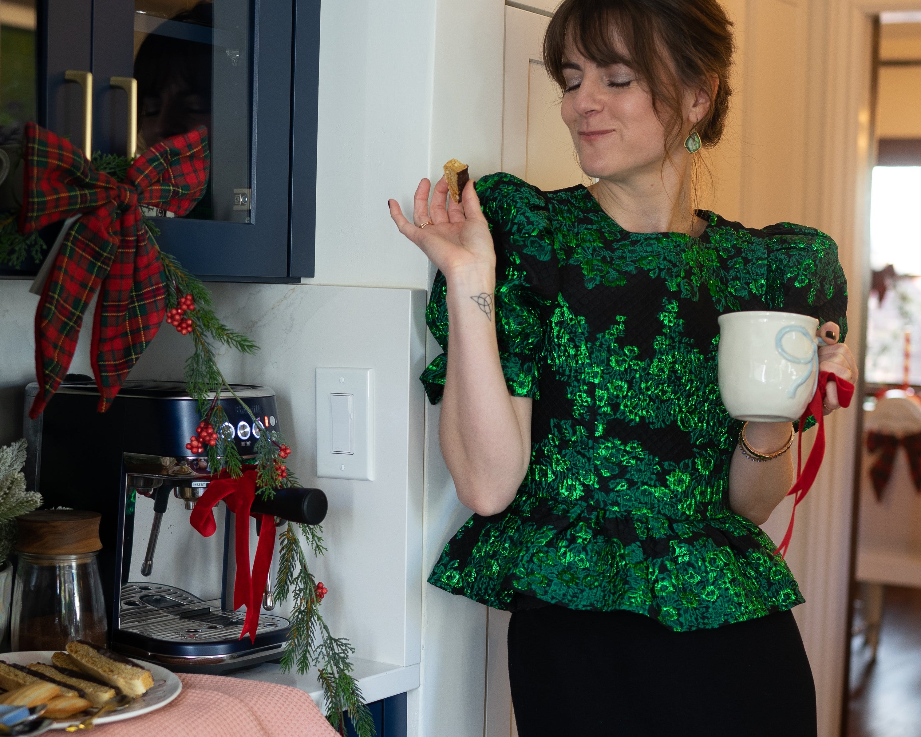 Woman in a green top and black skirt standing in a kitchen doorway.