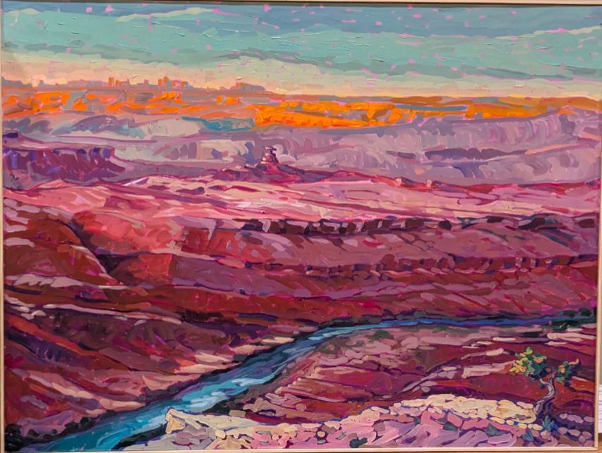 A red rock canyon at sunset. The canyon is bright hues of pink, red, purple, and orange. A river runs through the canyon.