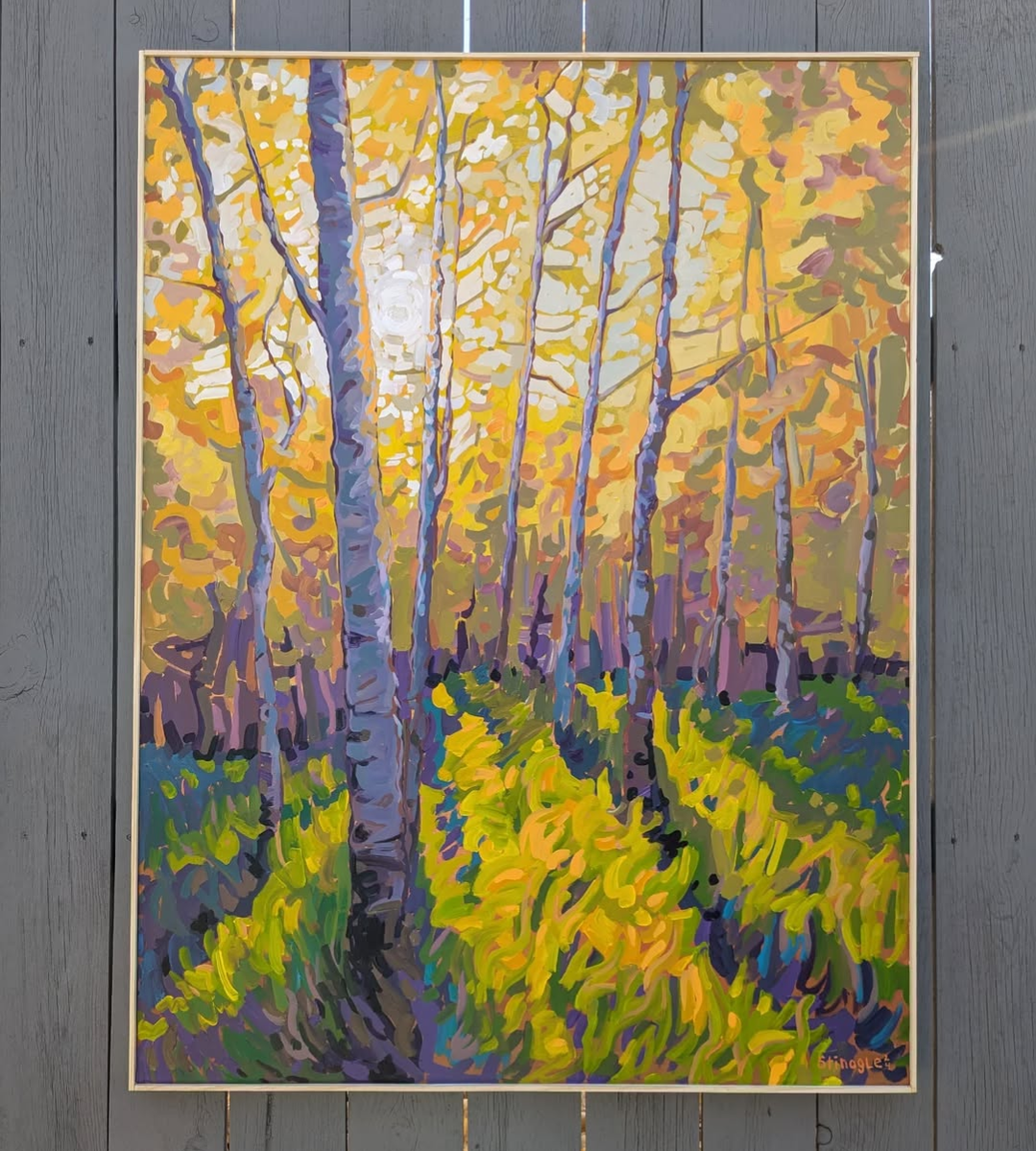 A bright fall scene in aspen trees. The leaves are orange, green, and yellow. Hues of purple and blue are scattered throughout.