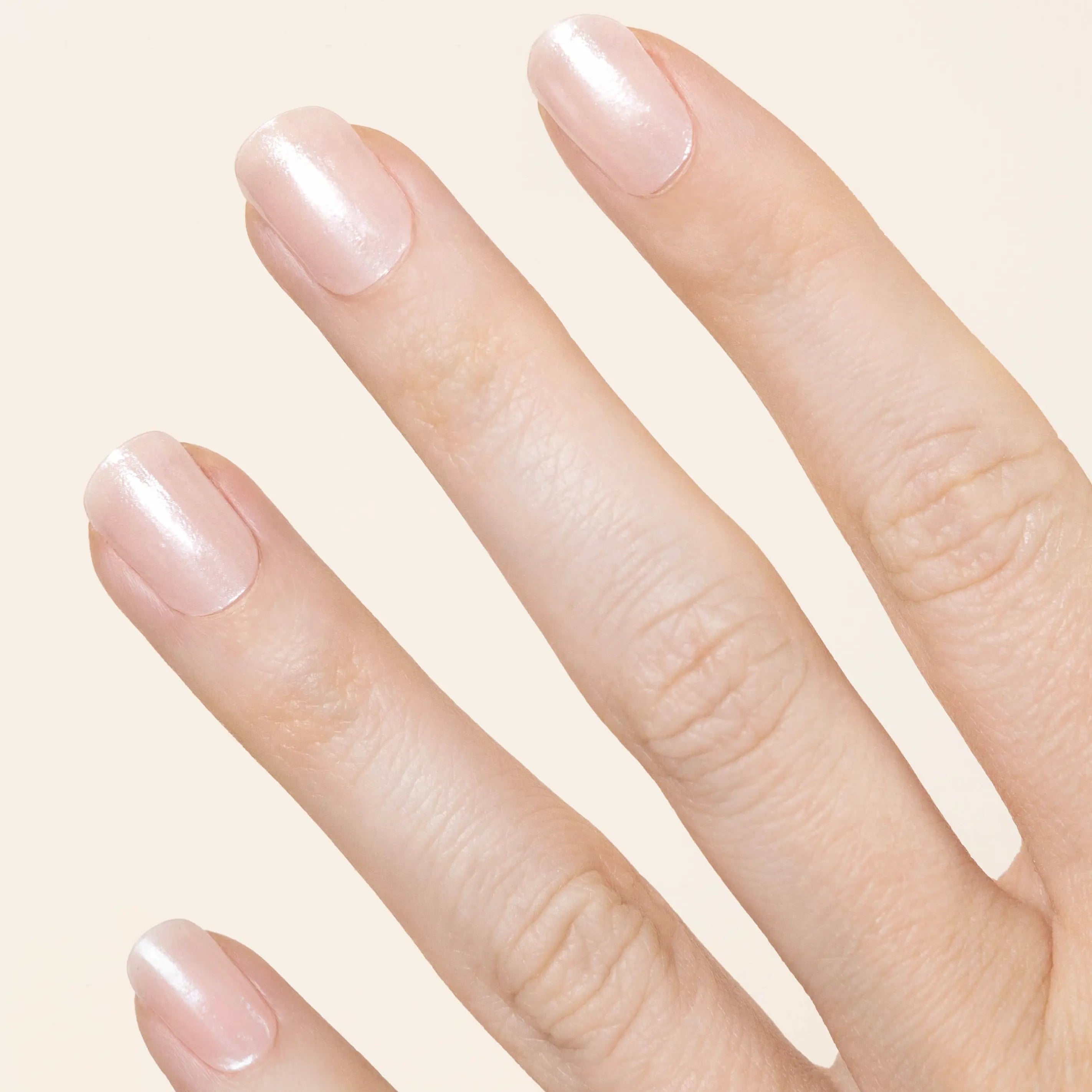 a hand showing 4 fingers featuring subtle pearly pale pink nails