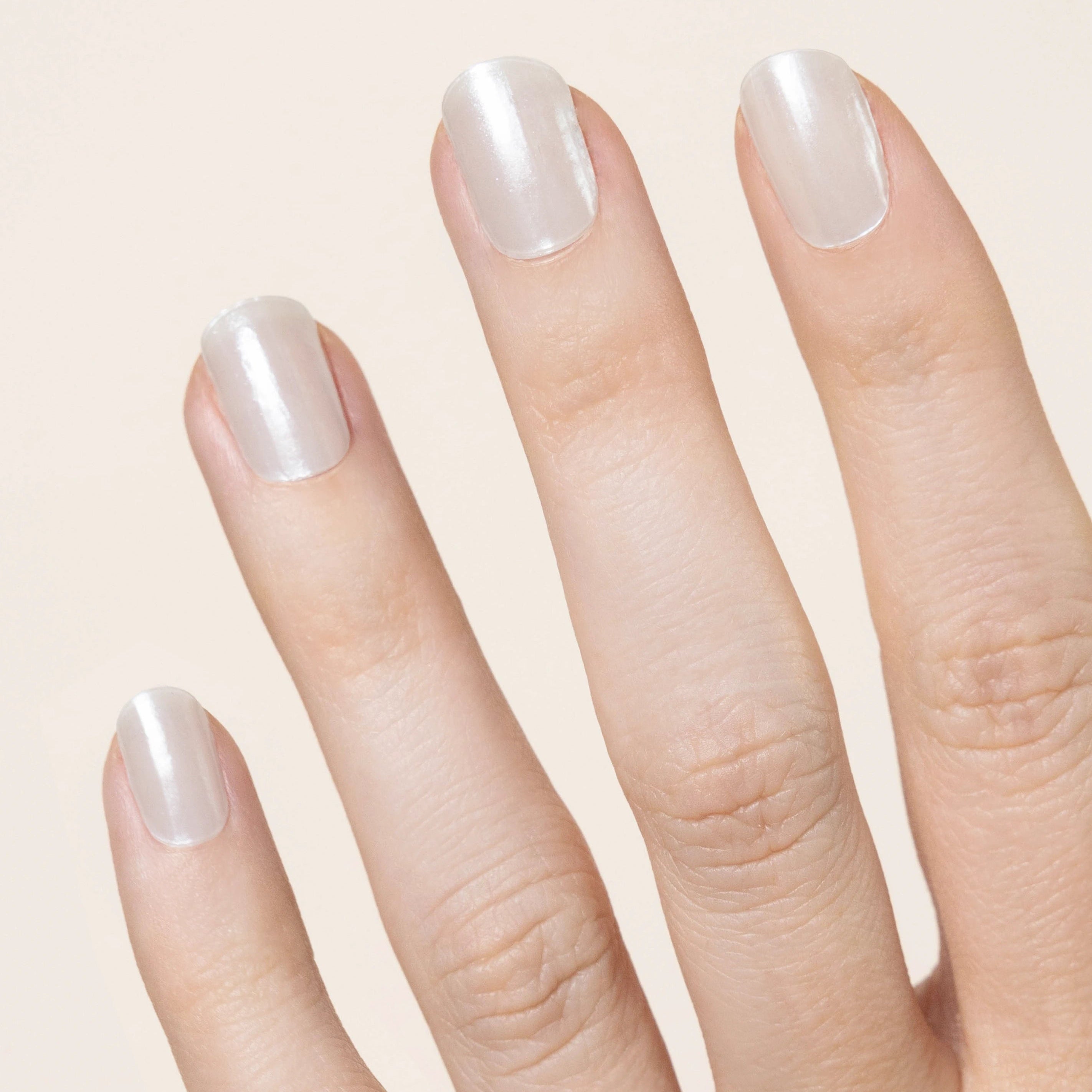 hand showing 4 fingers with a pearly white vanilla chrome effect on the nails