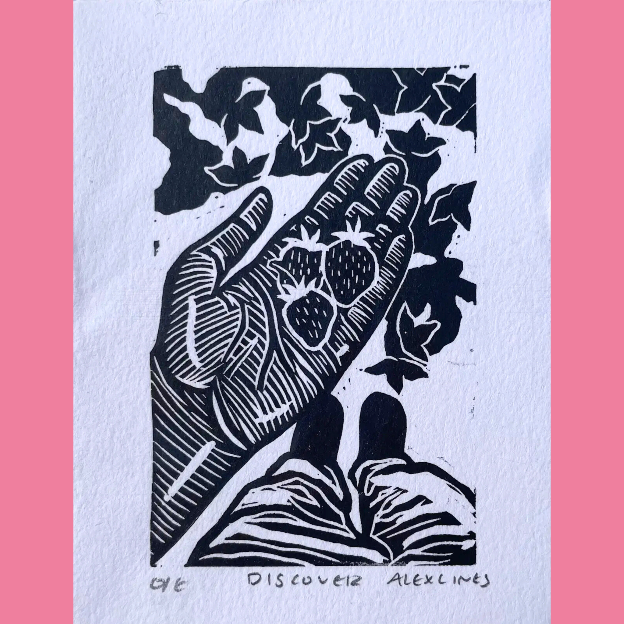 A black-and-white linocut print shows an open hand with palm facing up, cradling several strawberries surrounded by leafy vines and foliage, emerging from an open book with visible pages below. The artwork is printed on white paper with the title "DISCOVER" (numbered 012) and the signature "ALEX LINES" written beneath, framed by a bright pink border.