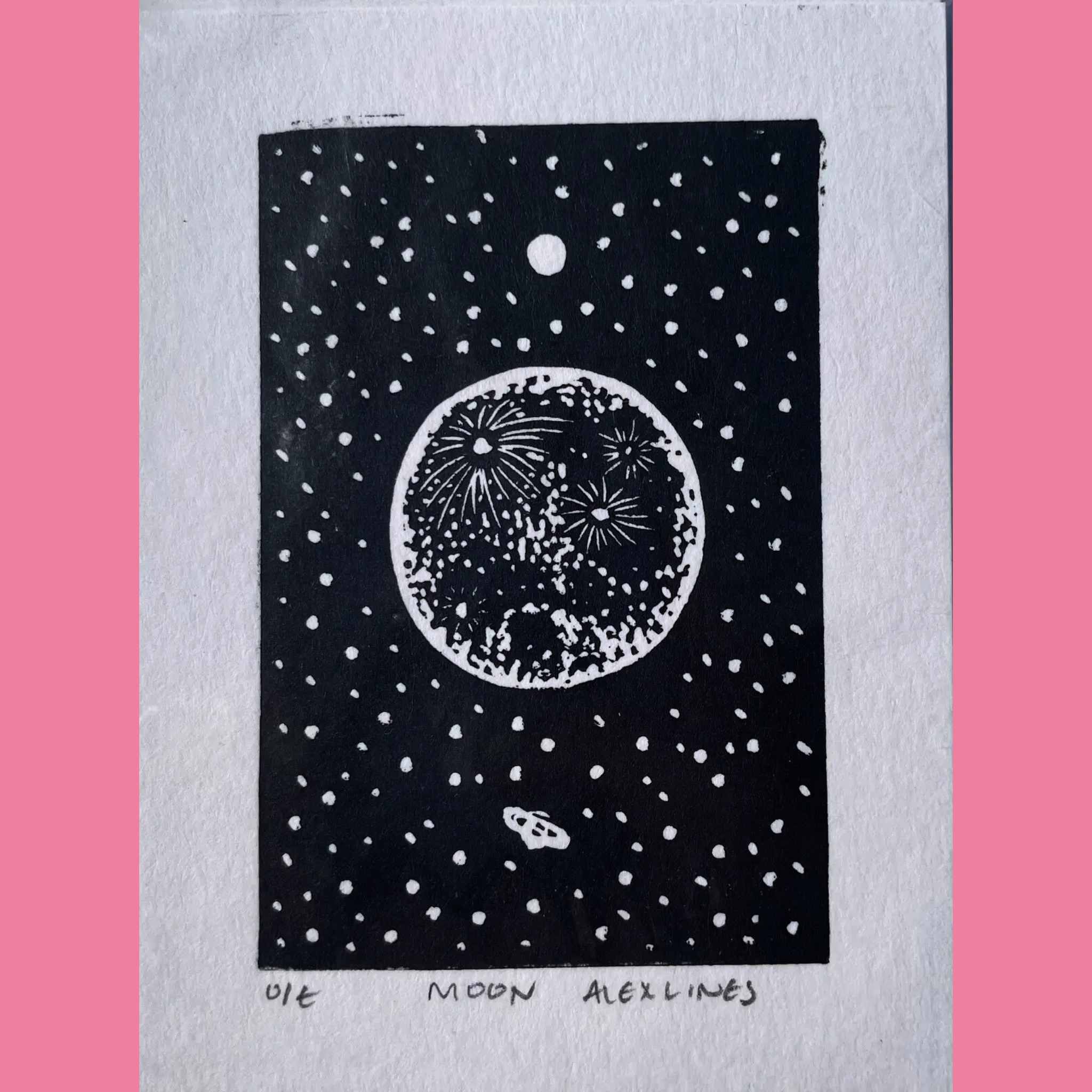 A black-and-white linocut print depicts a large, textured full moon with intricate white burst patterns and craters, glowing against a starry night sky filled with scattered white dots, while a small rocket or spaceship trails below it. The artwork is printed on white paper with the title "MOON," the number "DIE," and the signature "ALEX LINES" written beneath, surrounded by a bright pink border.