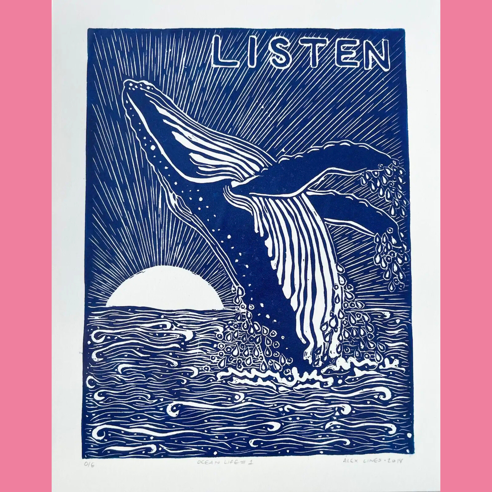 A bold blue-and-white linocut print portrays a powerful humpback whale breaching from the ocean, its massive fluke and pectoral fin raised high with water droplets trailing down, set against radiating sunbeams from a large white sun low on the horizon and wavy ocean lines below. The word "LISTEN" is prominently displayed in large white capital letters at the top, with the print titled "OCEAN LIFE #1," numbered "016," and signed "ALEX LINES • 2019" at the bottom, all framed by a bright pink border.