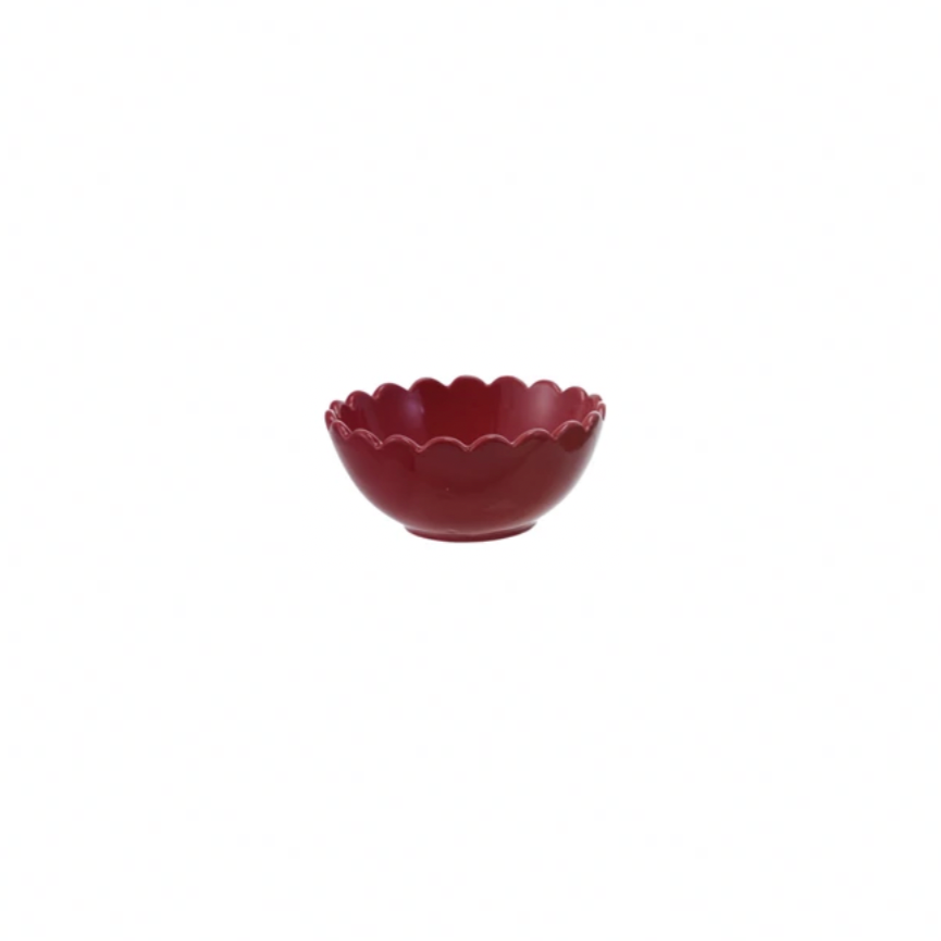 Red ceramic bowl with scalloped edge on a white background