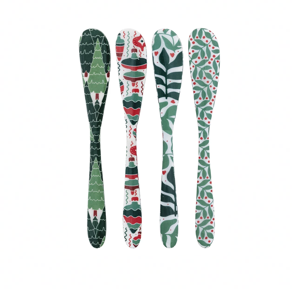 Four decorative spoons with green, red, and white patterns on a white background