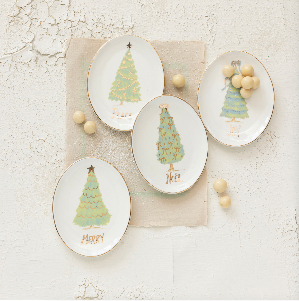 Set of decorative plates with Christmas tree designs on a textured surface.