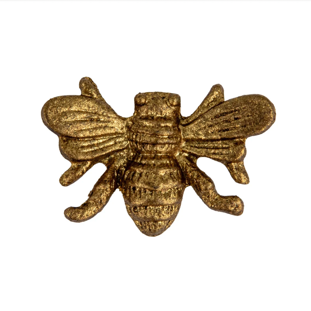 Gold bee-shaped magnet on a white background