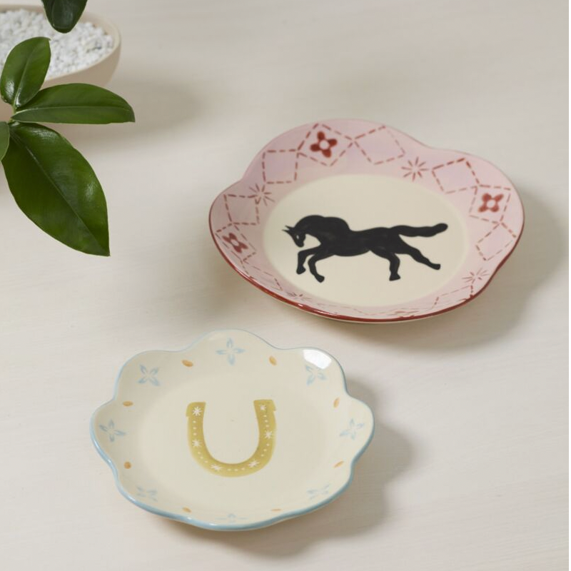 Two decorative plates on a light surface with a plant leaf in the corner.