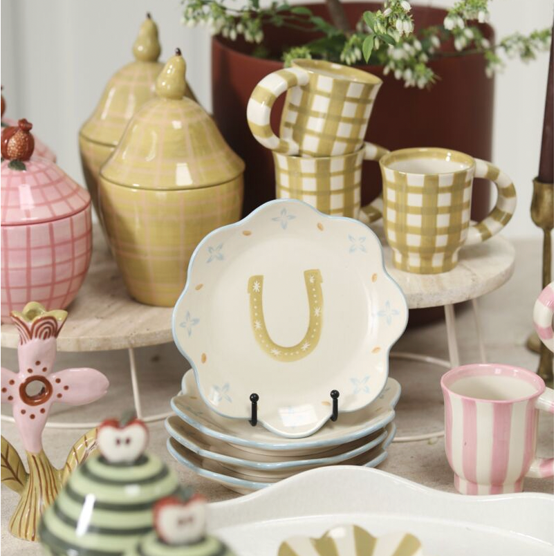 Collection of ceramic items including mugs, plates, and decorative pieces on a surface.