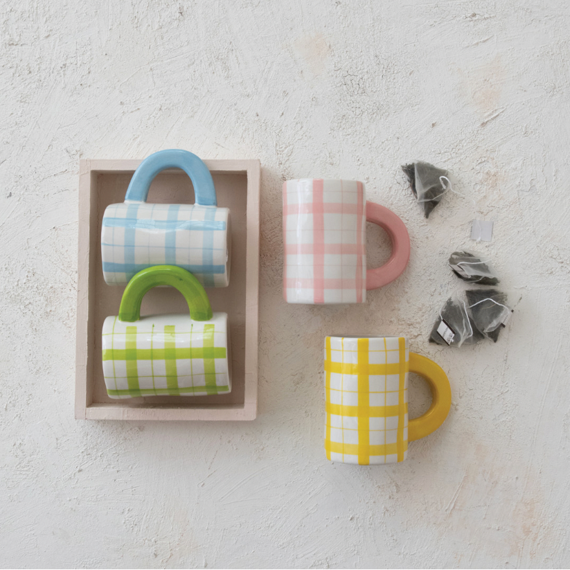 Colorful ceramic mugs in a wooden box on a light textured surface