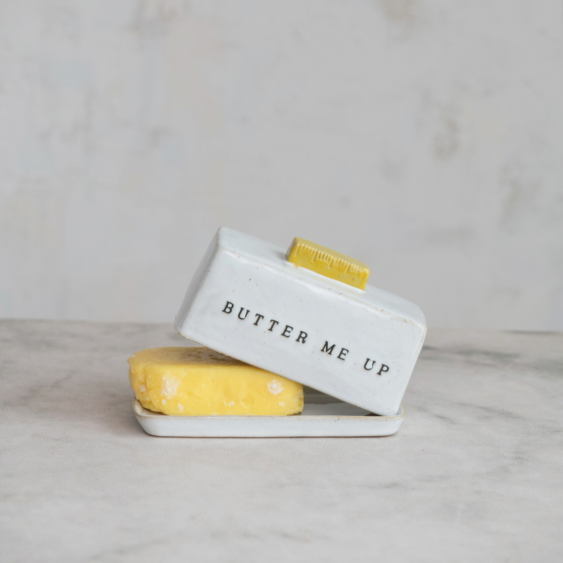 Butter dish with 'BUTTER ME UP' text on a marble surface