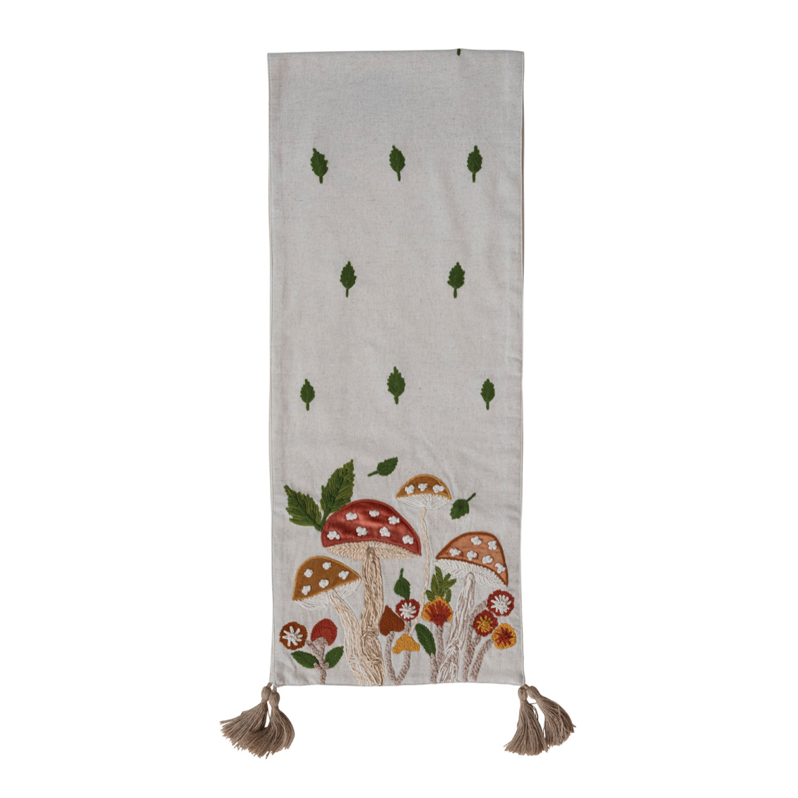 A vertical beige fabric runner or scarf with embroidered green leaves and a colorful mushroom design near the bottom, finished with two brown tassels.